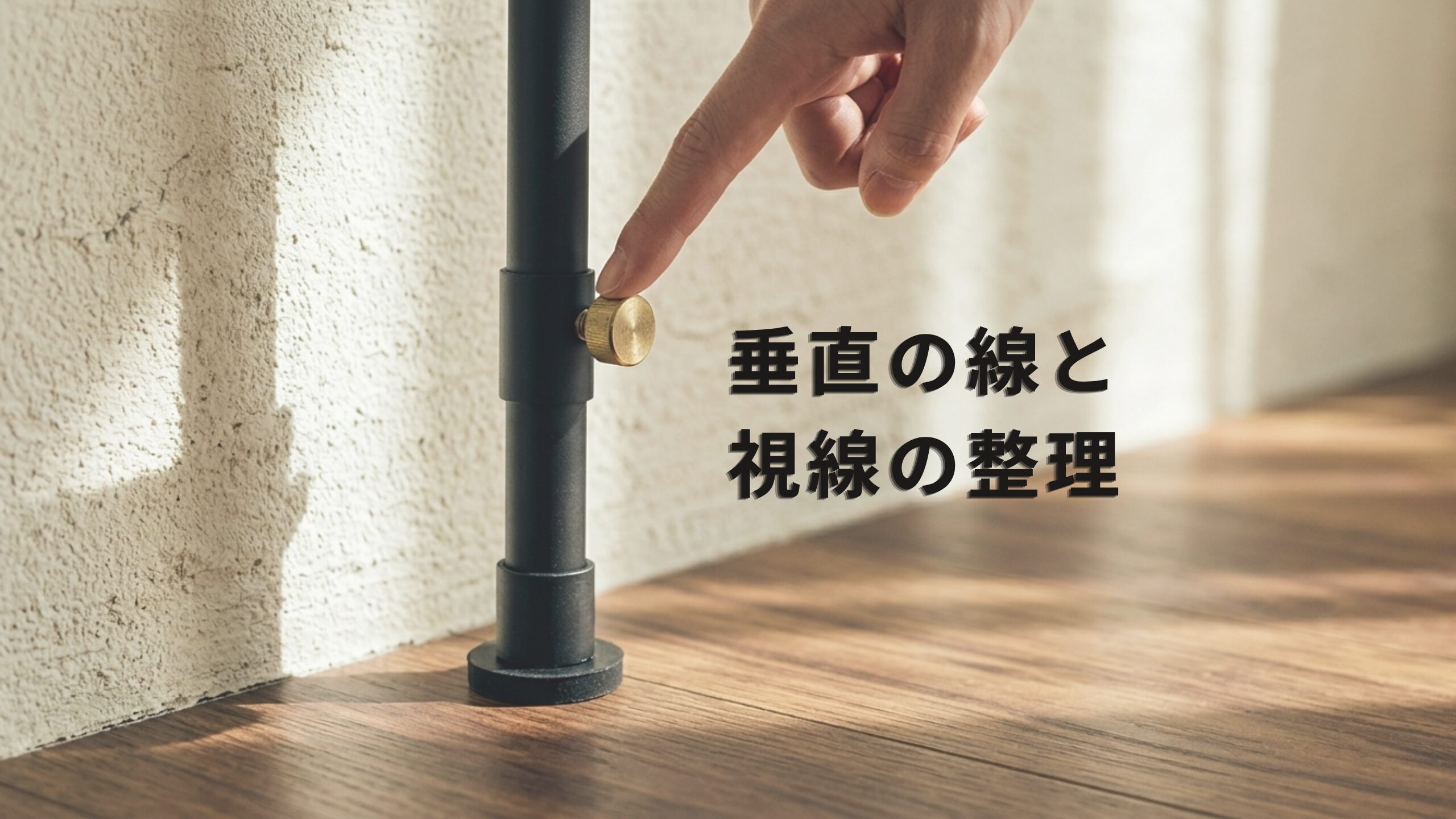 リビングの壁際に垂直に設置された、真鍮のネジが付いた黒いスチール製の突っ張り棒。