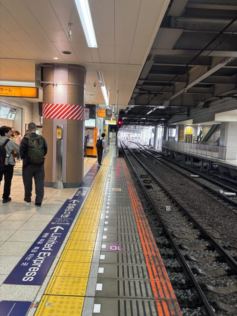 北千住駅ホームの特急乗り場案内とリュック姿の一行
