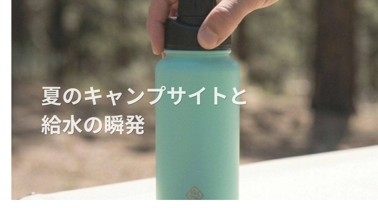 キャンプテーブルに置かれ、指でキャップのボタンが押されているステンレスボトル。