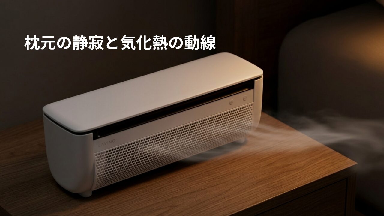 寝室のサイドテーブルに置かれ、前面グリルから横方向にミストを放出している白いポータブルクーラー。